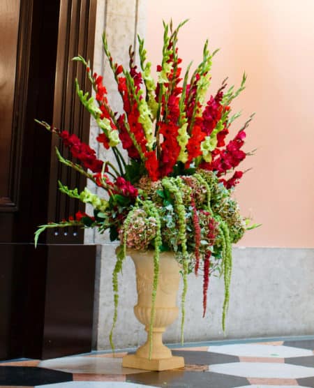 Red and green wedding flowers in large vase on floor
