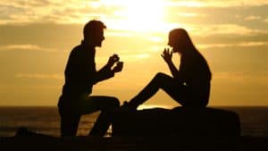 guy proposing to girl wth sunset behind them