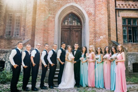 Bridal party in pink and blue dresses standing in a line with bride and groom 