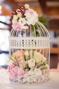 white vintage decorative birdcage filled with white and pastel colored roses and spring flowers