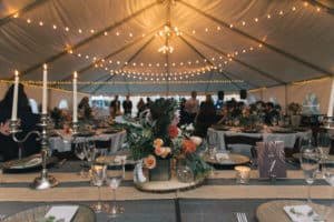 Cafe lights and chandeliers inside tent at wedding reception