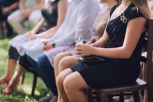 Woman in black dressing holding a glass of champagne during wedding ceremony