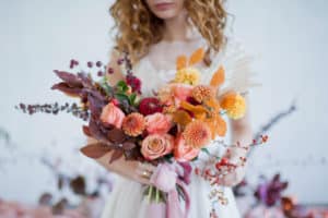 Bride holding her bouquet with orange, pink, and red flowers