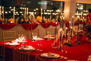 Festive table decor. Red colors with golden cutlery and candles. Wedding, party, birthday. Autumn table setting. Fork and knife, napkin, pumpkin. Halloween or Thanksgiving day background