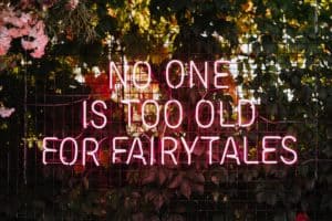 No one is too old for fairytales - neon sign on a wall at an outdoor wedding party. Love concept