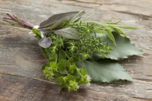 Fresh bouquet garni with different herbs on an old wooden table