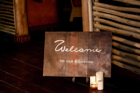 Wooden welcome table board sign at the wedding on the beach with welcoming romantic words during destination wedding marriage ceremony, invitation for the guests