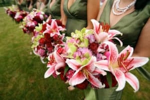 Bridesmaids in green dresses holding magenta and green floral bouquets