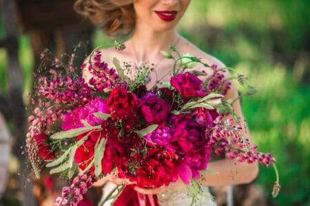 The bride holds a chic wedding bouquet of roses and peony.